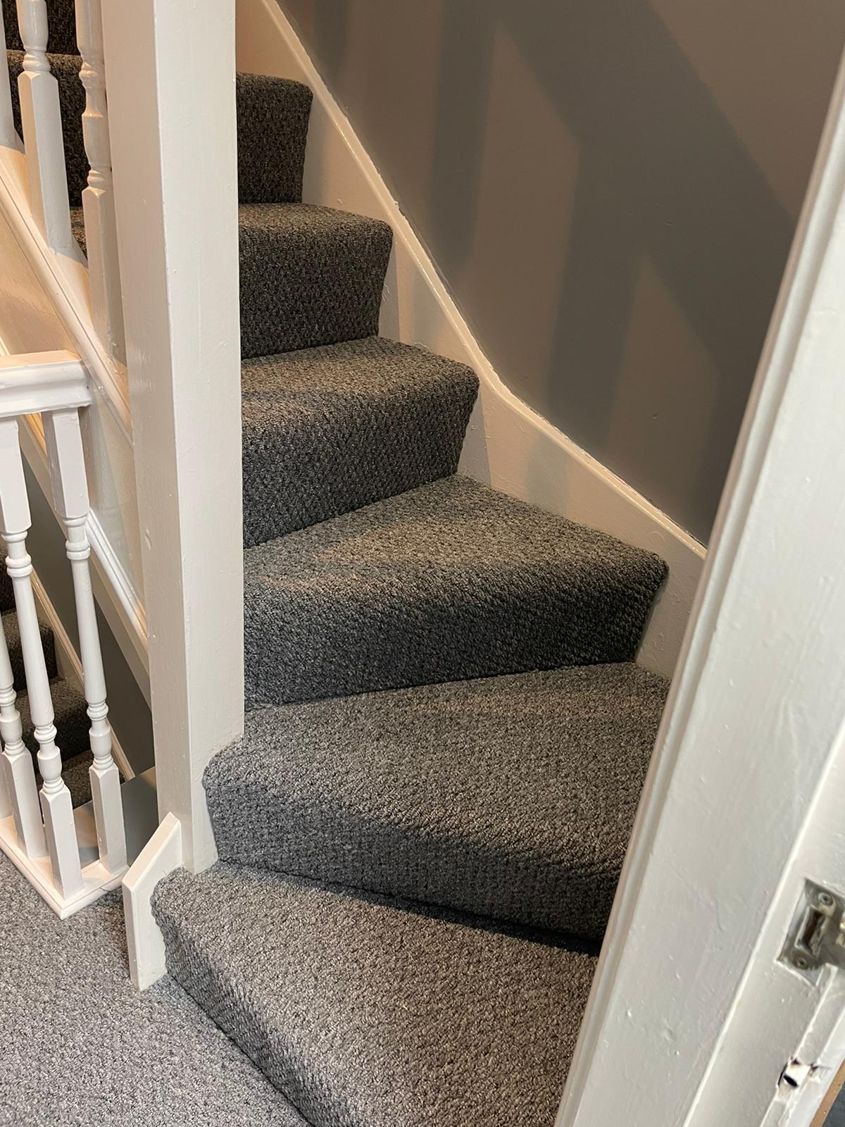 A set of stairs with a carpeted staircase and a white railing.