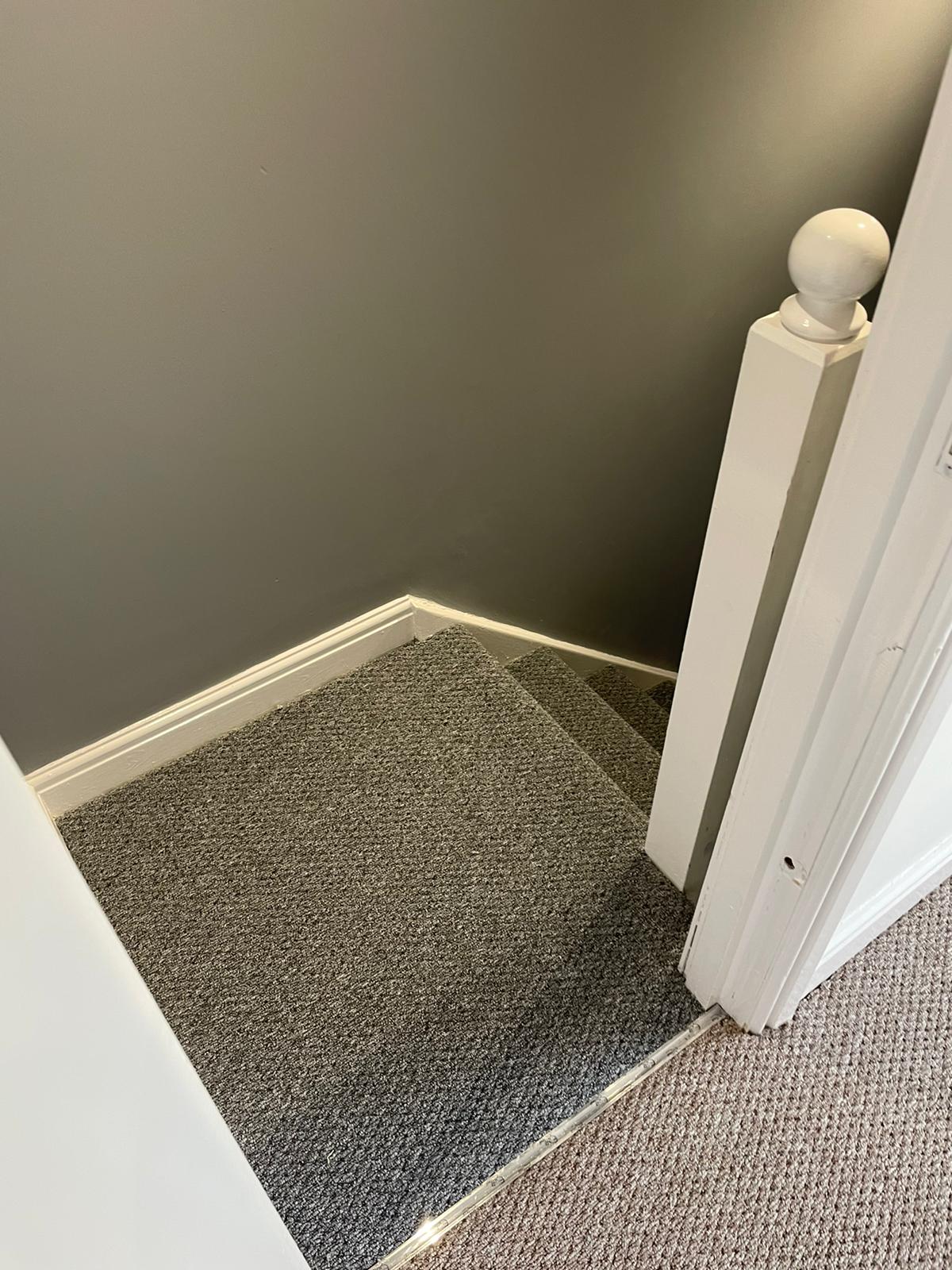 A staircase with a carpeted floor and a white railing.