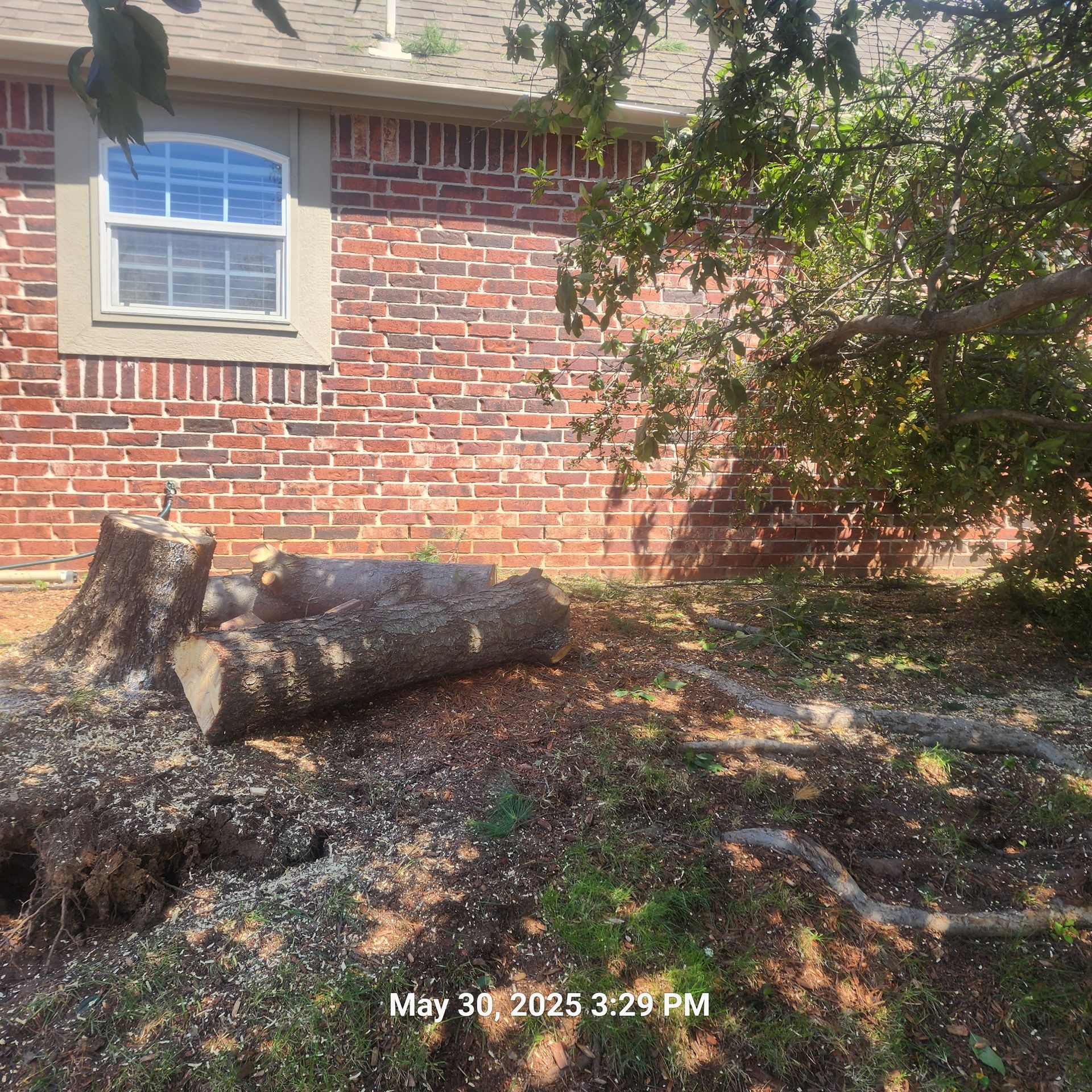 A brick house with a tree stump in front of it.