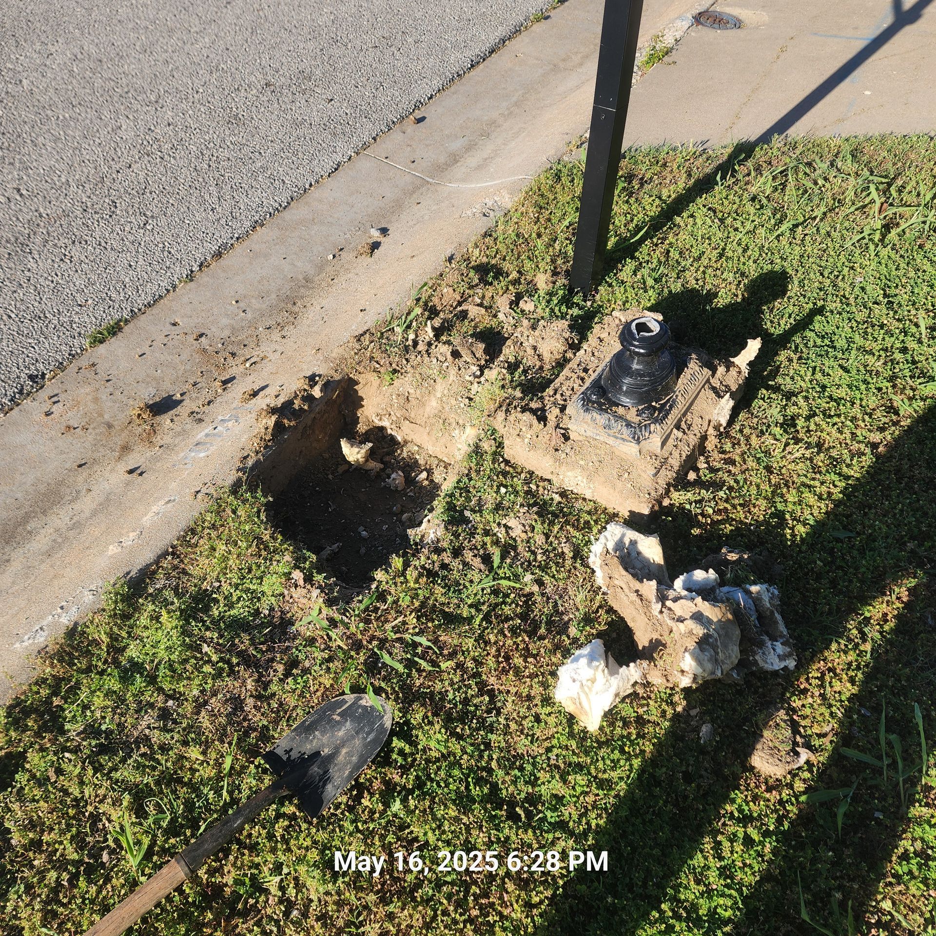A shovel is laying in the grass next to a pole