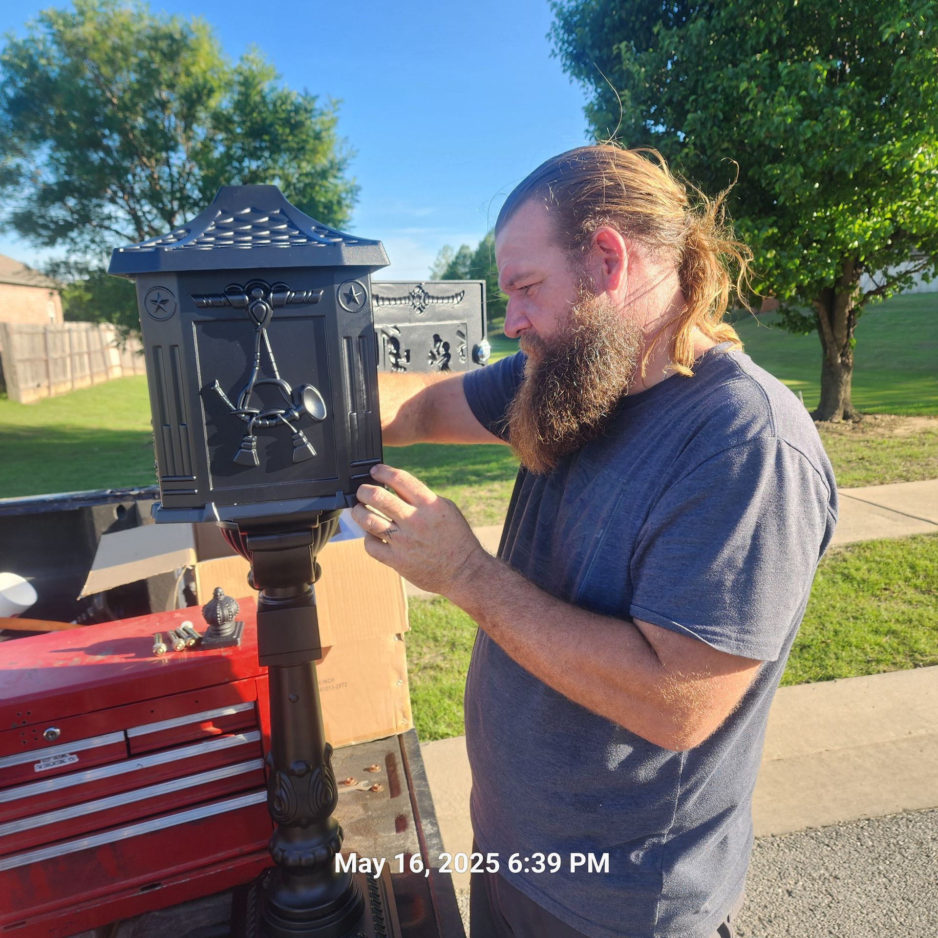 A man with a beard is fixing a mailbox on may 18th at 6:39 pm