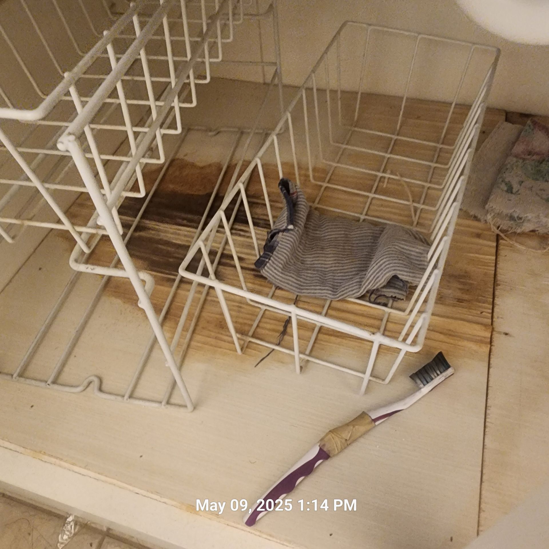A toothbrush is laying on a counter next to a wire basket