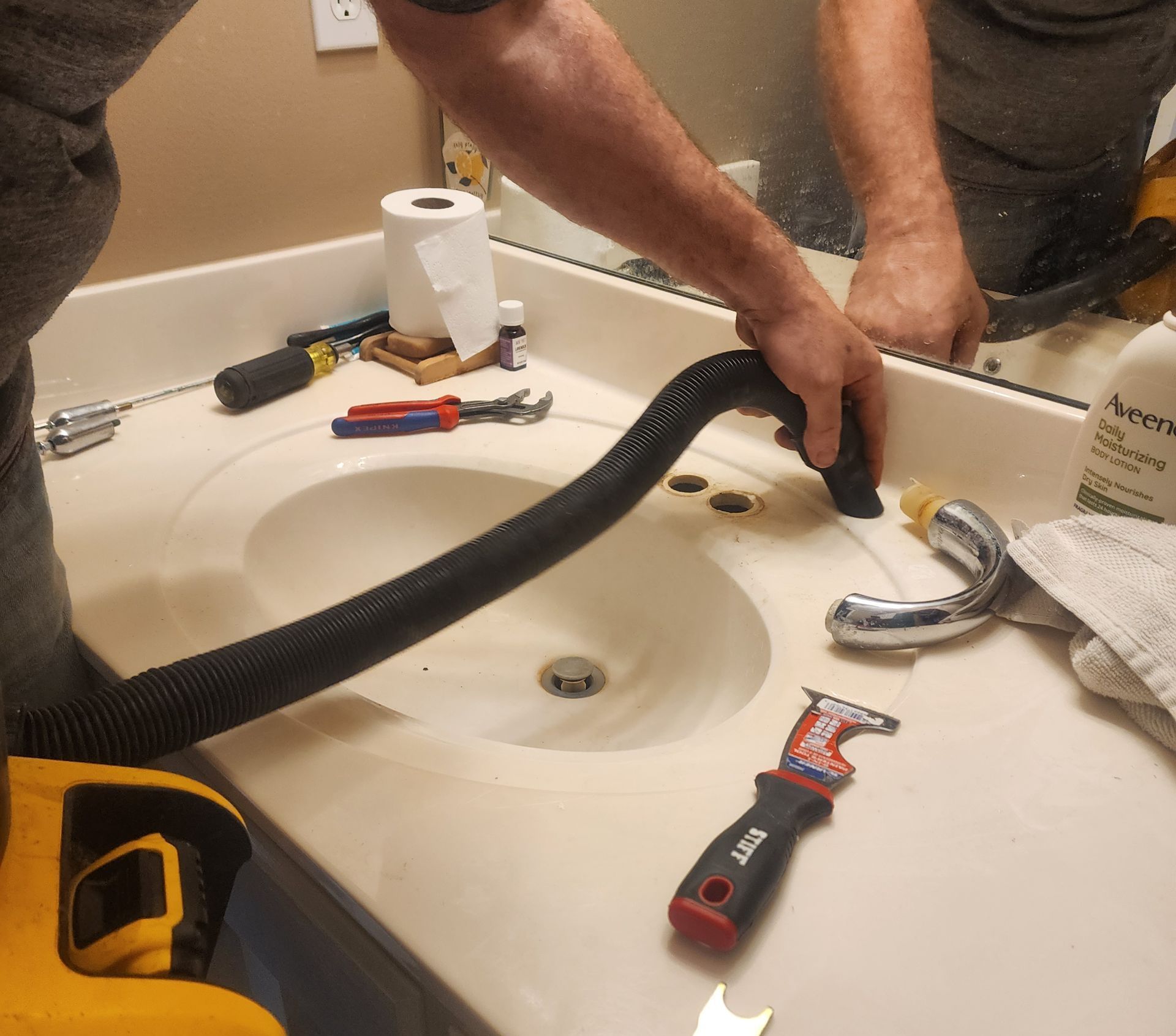 A man is using a vacuum cleaner to clean a bathroom sink