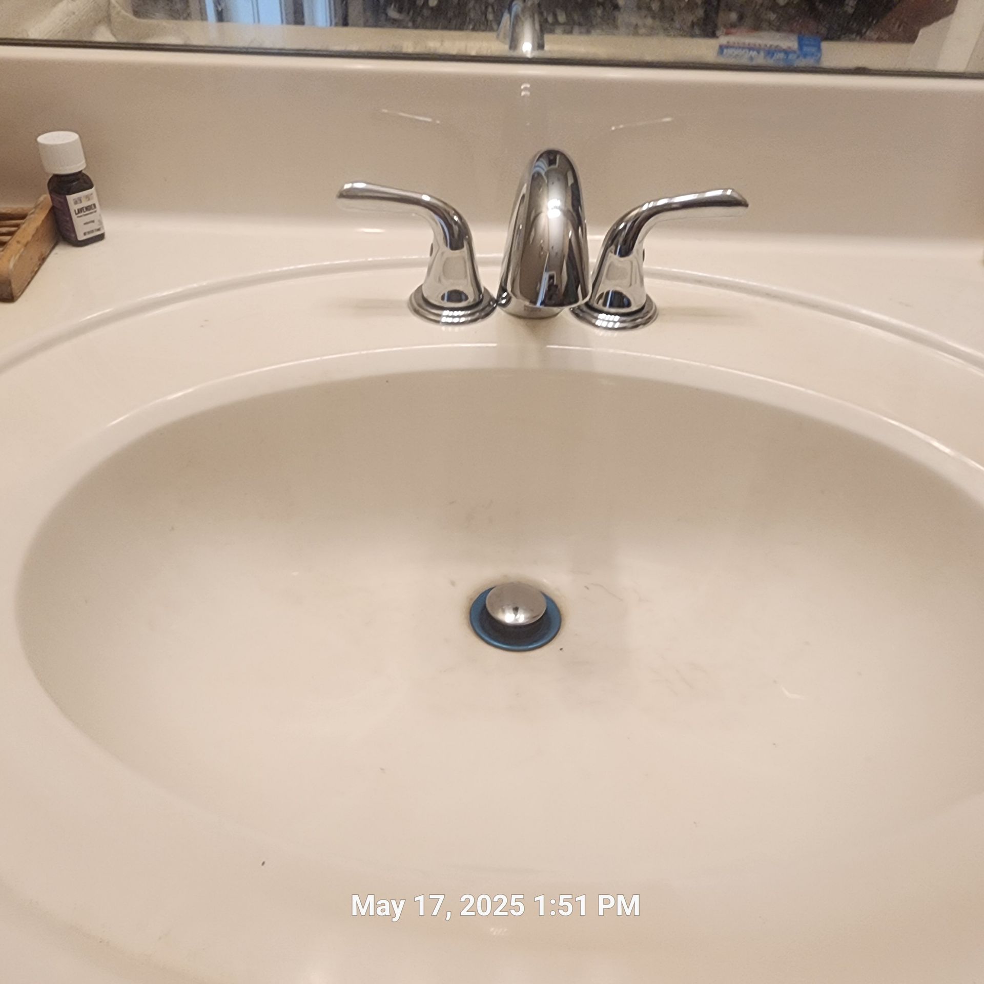 A bathroom sink with a bottle of essential oil next to it
