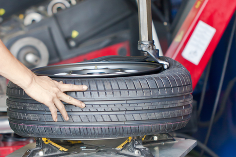 A person is changing a tire on a machine in a garage.