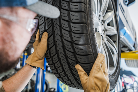 A man is holding a tire in his hands in a garage.