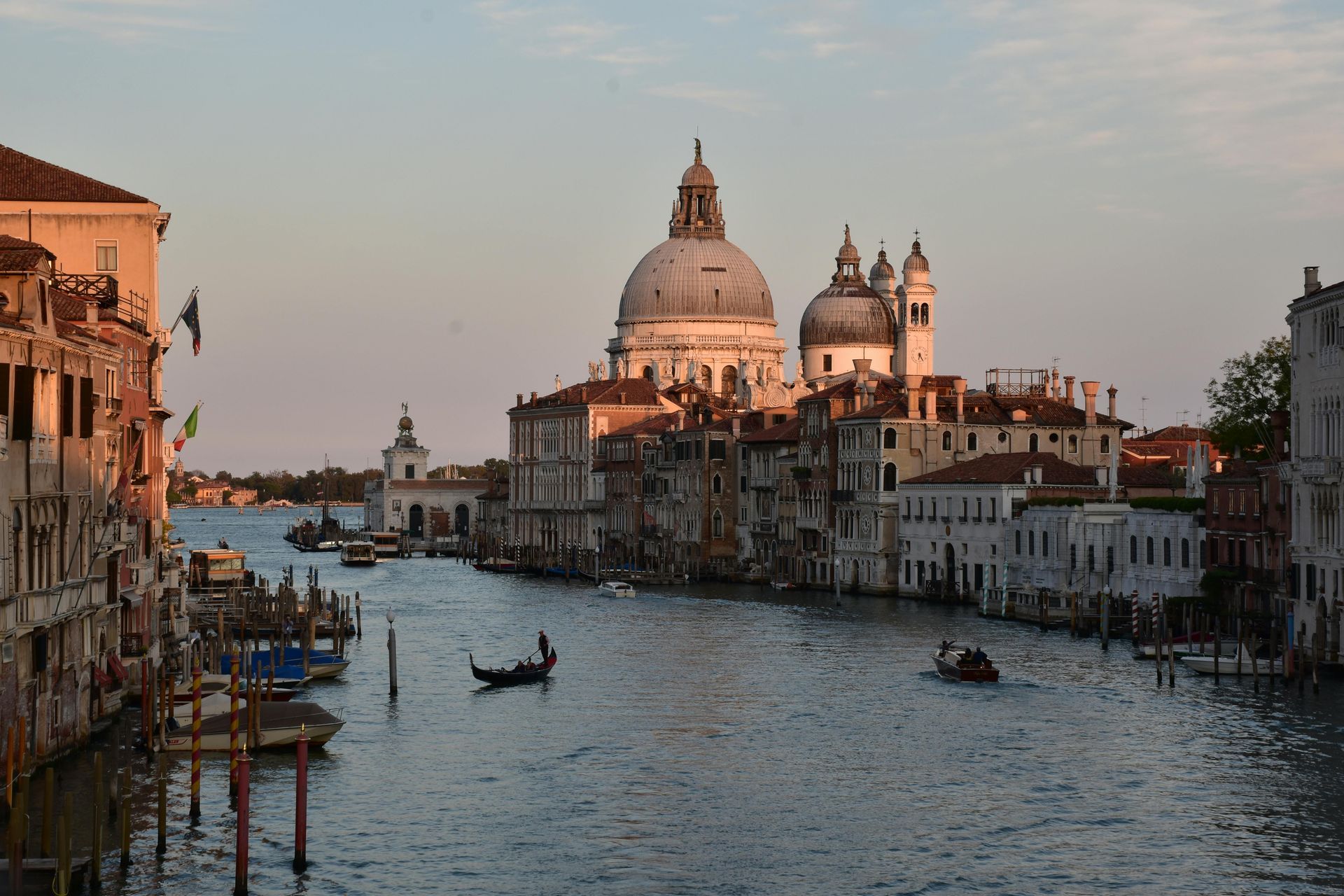 Grand Canal in Venice with boats and Basilica di Santa Maria della Salute at sunset.