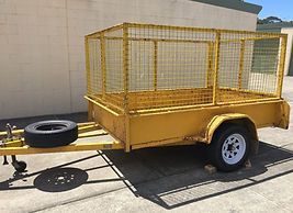 A Yellow Trailer With a Cage Attached to It is Parked in Front of a Building — Huskisson Self Storage in Huskisson, NSW