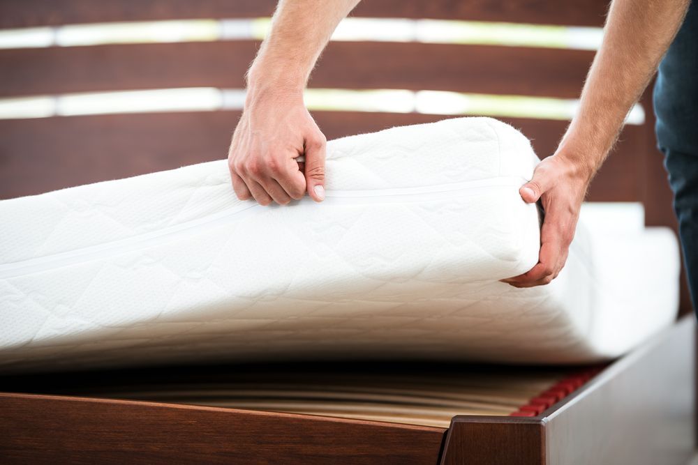 A Man is Putting a Mattress on a Bed — Huskisson Self Storage in Huskisson, NSW