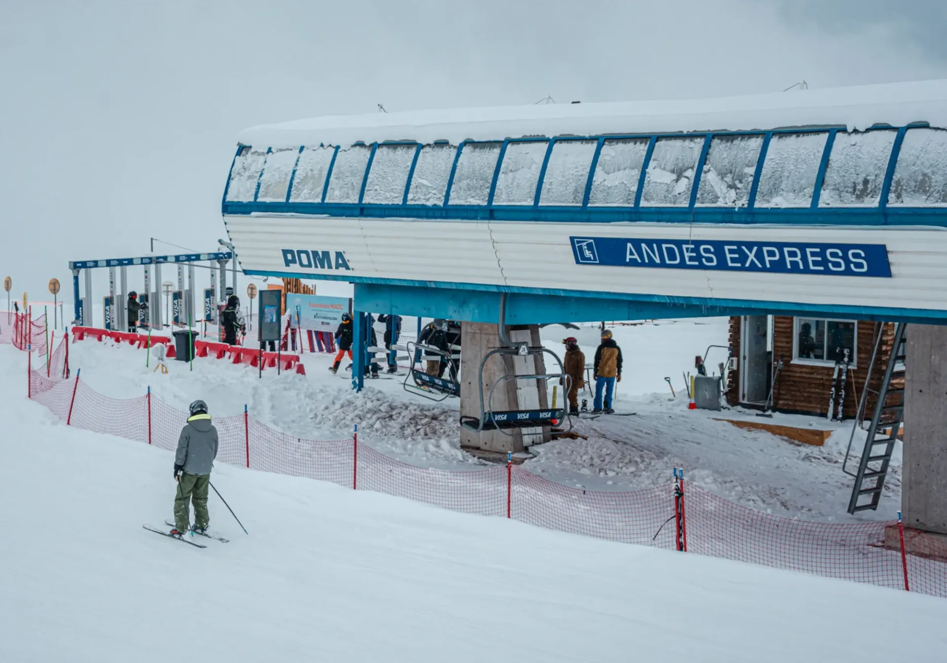 Ski lift station labeled Andes Express on a snowy mountain, with people waiting in line.