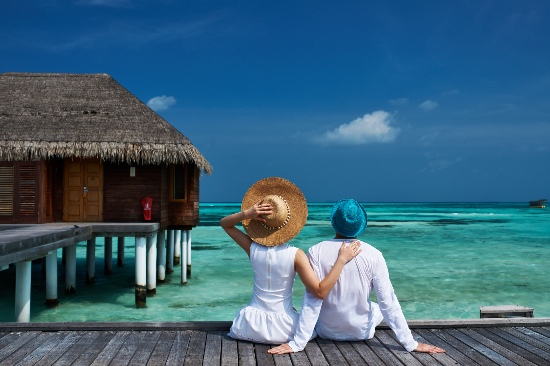 A man and a woman are sitting on a dock looking at the ocean.