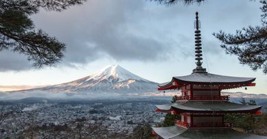 A pagoda with a mountain in the background and a city in the foreground.