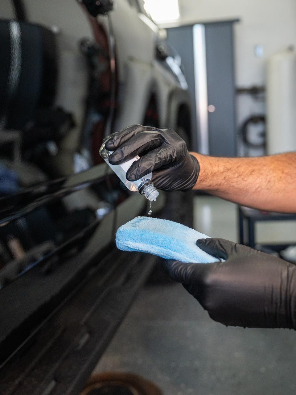 A person is applying a clear film to the hood of a car.
