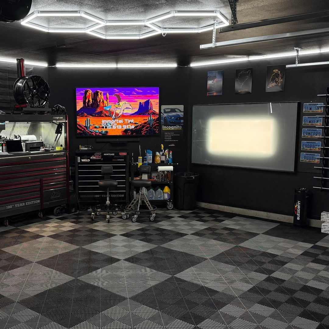 A man is cleaning the wheel of a black car with a sponge.