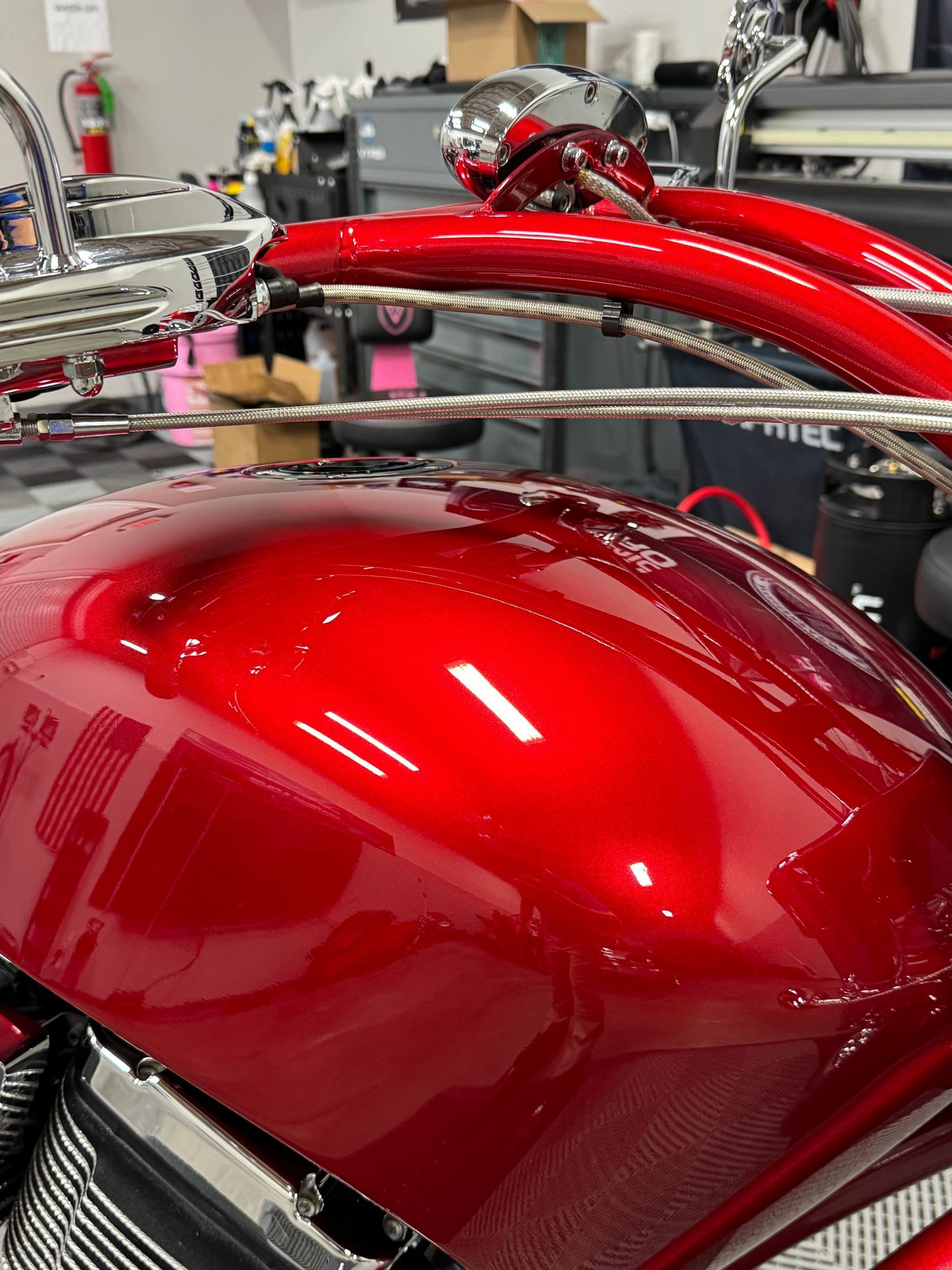 A red motorcycle is sitting on a table in a garage.