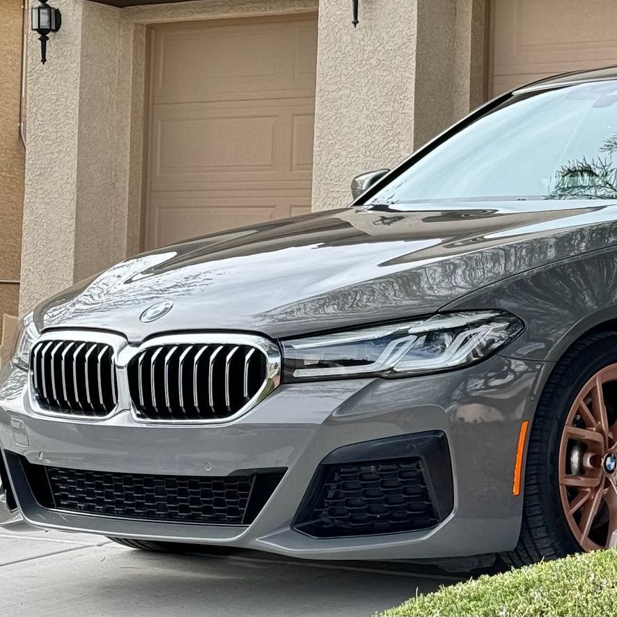 A gray bmw is parked in front of a garage door.