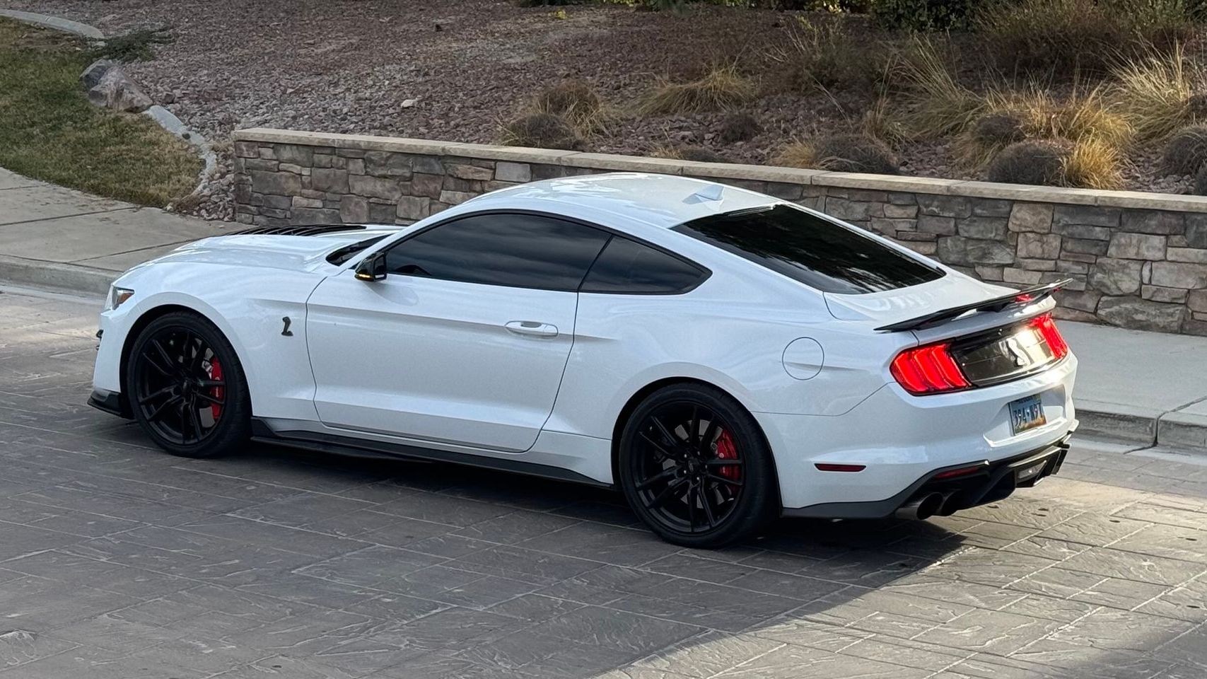 A white ford mustang is parked on the side of the road.