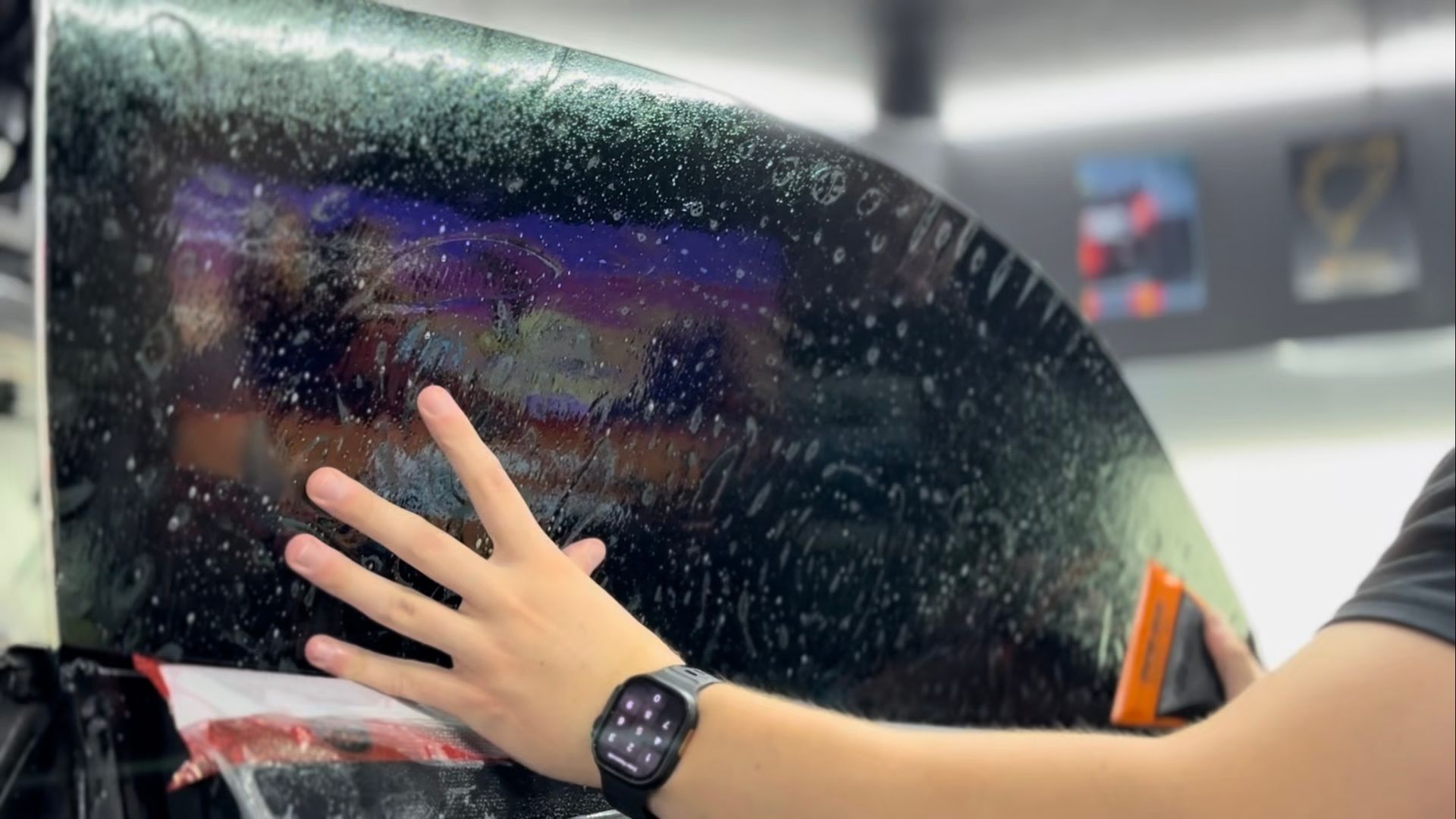 A person is applying window tinting to a car window.