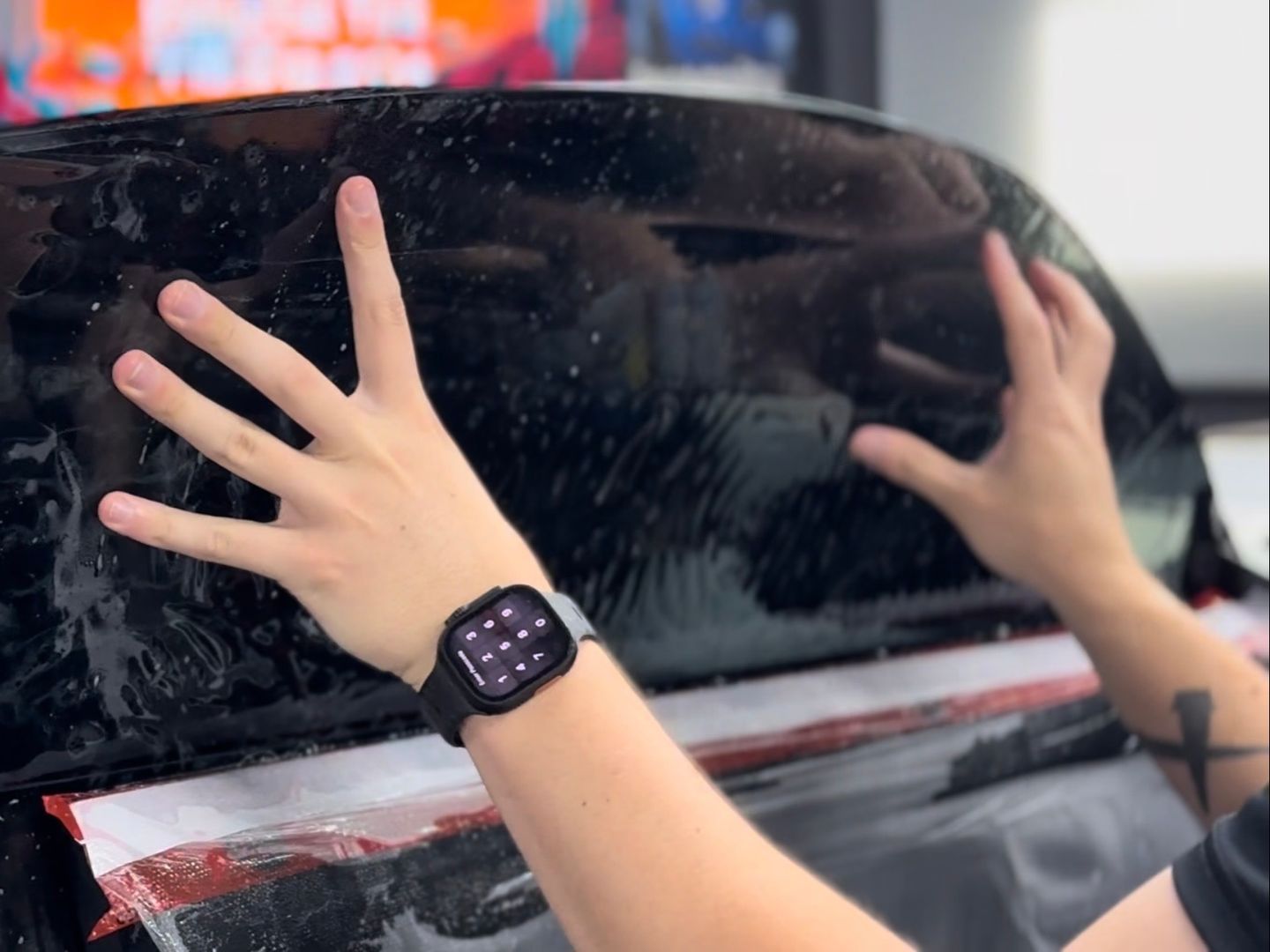 A person is cleaning a blue car with an orange towel