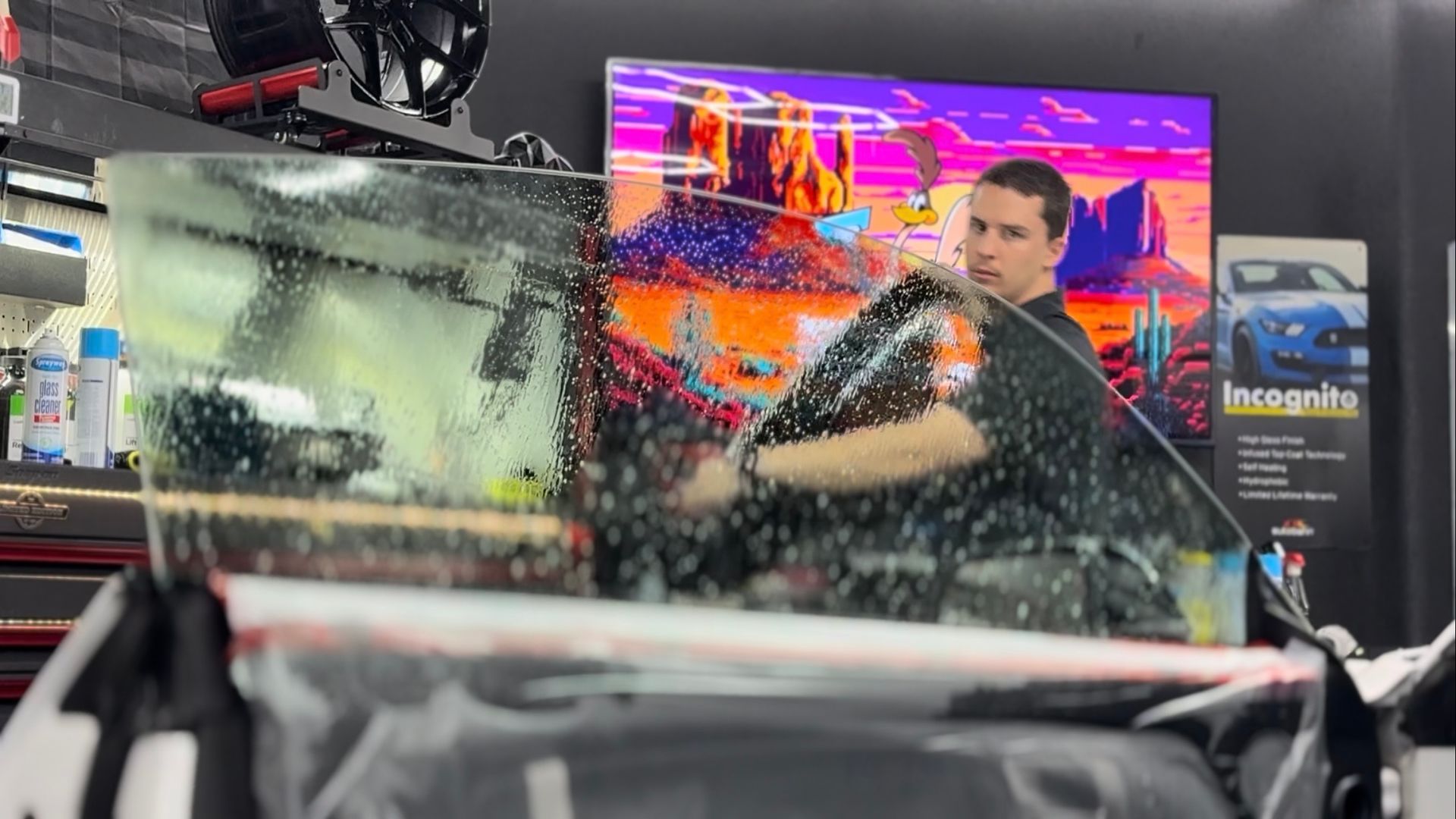 A man is cleaning the wheel of a black car with a sponge.