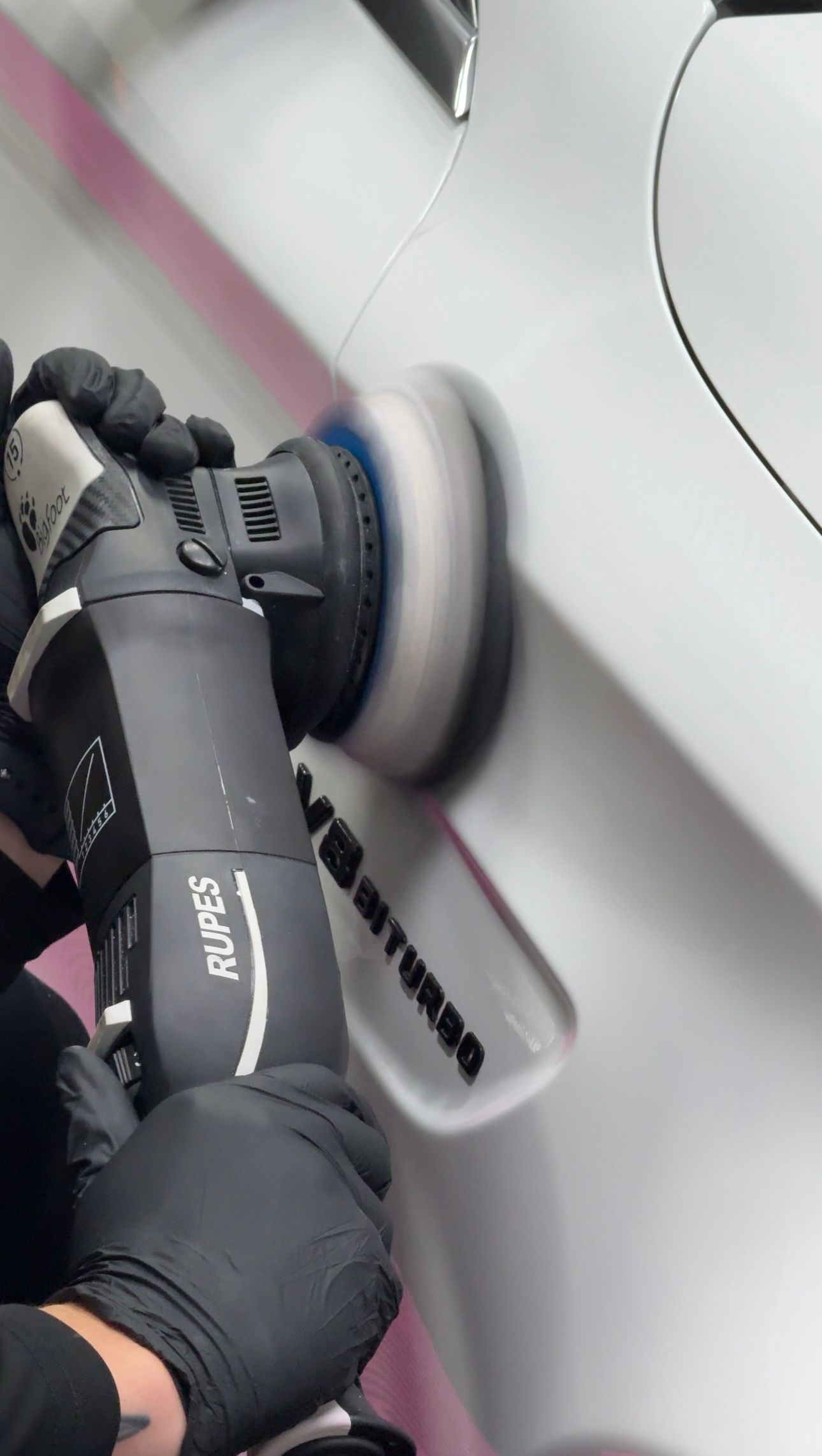 A car is covered in plastic wrap in a garage.