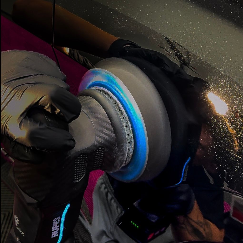 A person wearing a pair of raptor gloves polishing a car