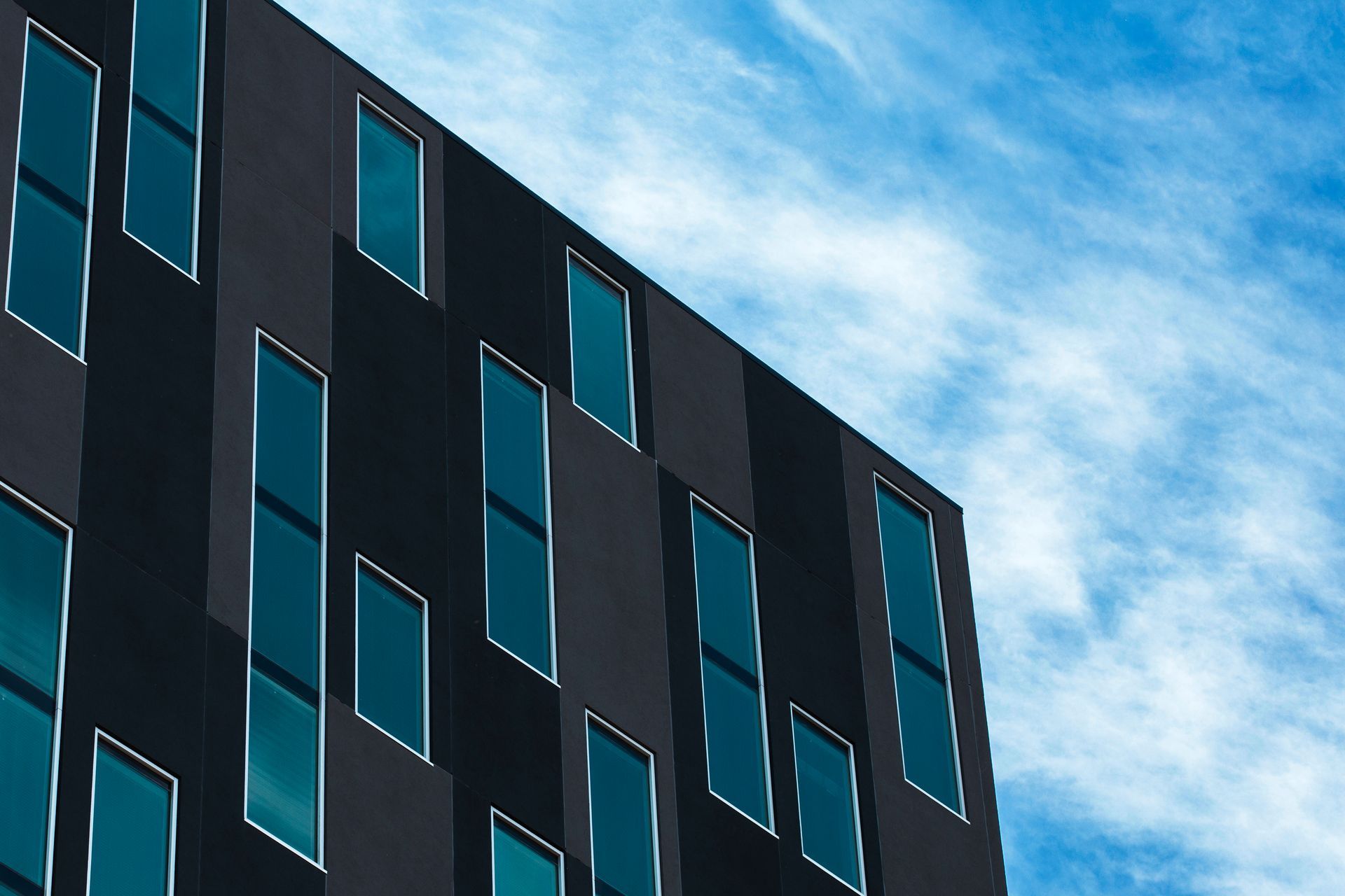 A black building with blue windows against a blue sky