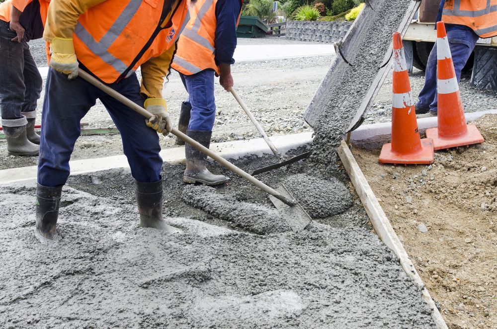 A Group Of Construction Workers Are Pouring Concrete On A Sidewalk — DCK Concreting In Laurieton, NSW