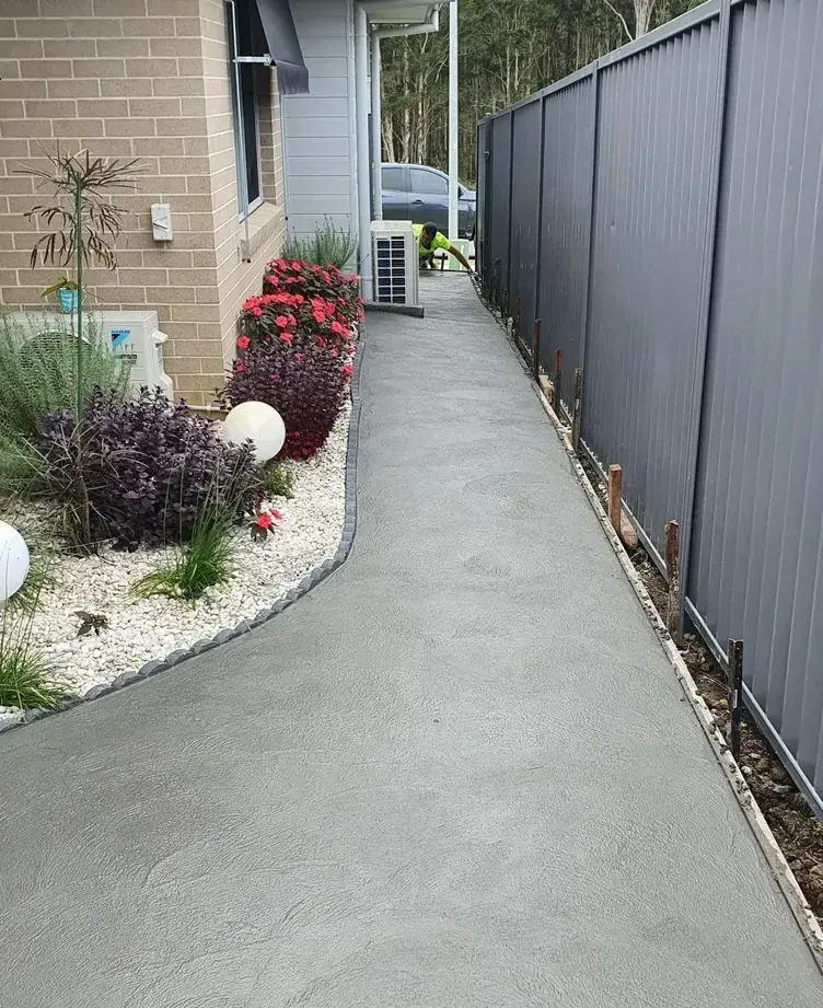 A Concrete Walkway Leading To A House Next To A Fence — DCK Concreting In Lake Cathie, NSW