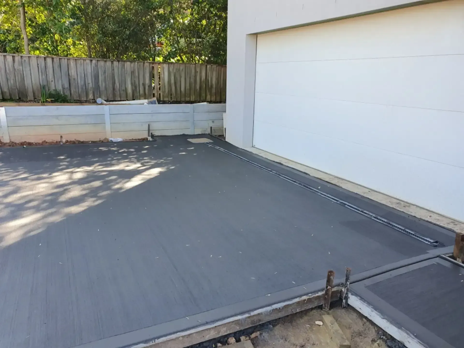 A Concrete Driveway Is Being Built Next To A Garage Door — DCK Concreting In Lake Cathie, NSW