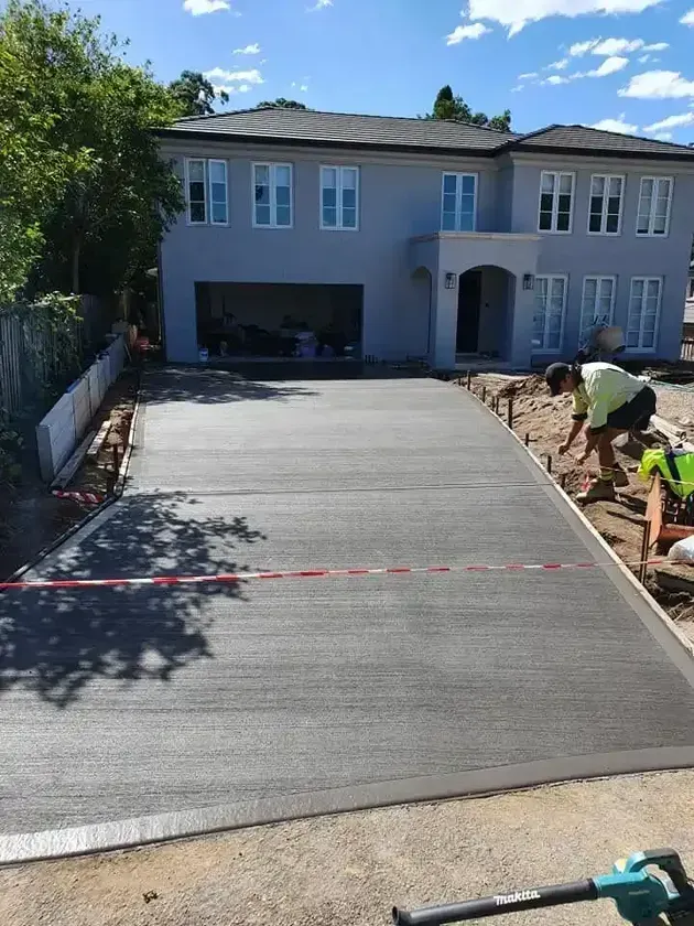 A Concrete Driveway Is Being Built In Front Of A Large House — DCK Concreting In Port Macquarie, NSW