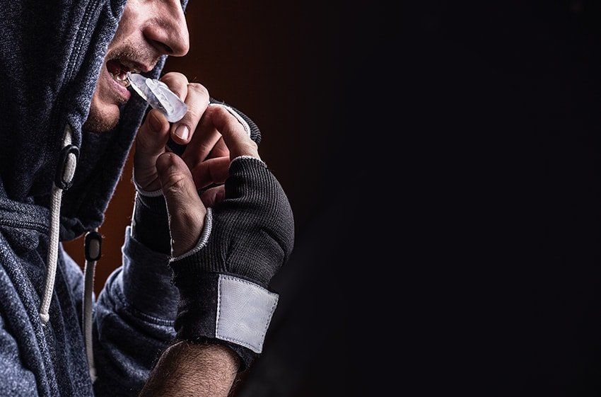 Man training puts in his mouthguard. He understands the Importance of Mouthguards