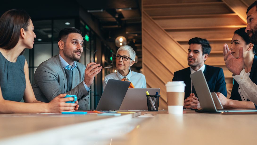 A group of people are sitting around a table having a meeting.
