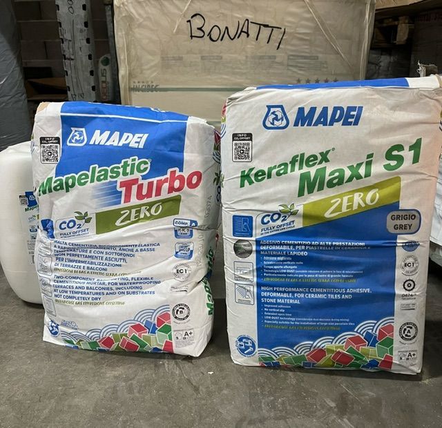 Due sacchi di materiali edili Mapei: Mapelastic Turbo Zero e Keraflex Maxi S1 Zero, su un pavimento in calcestruzzo.