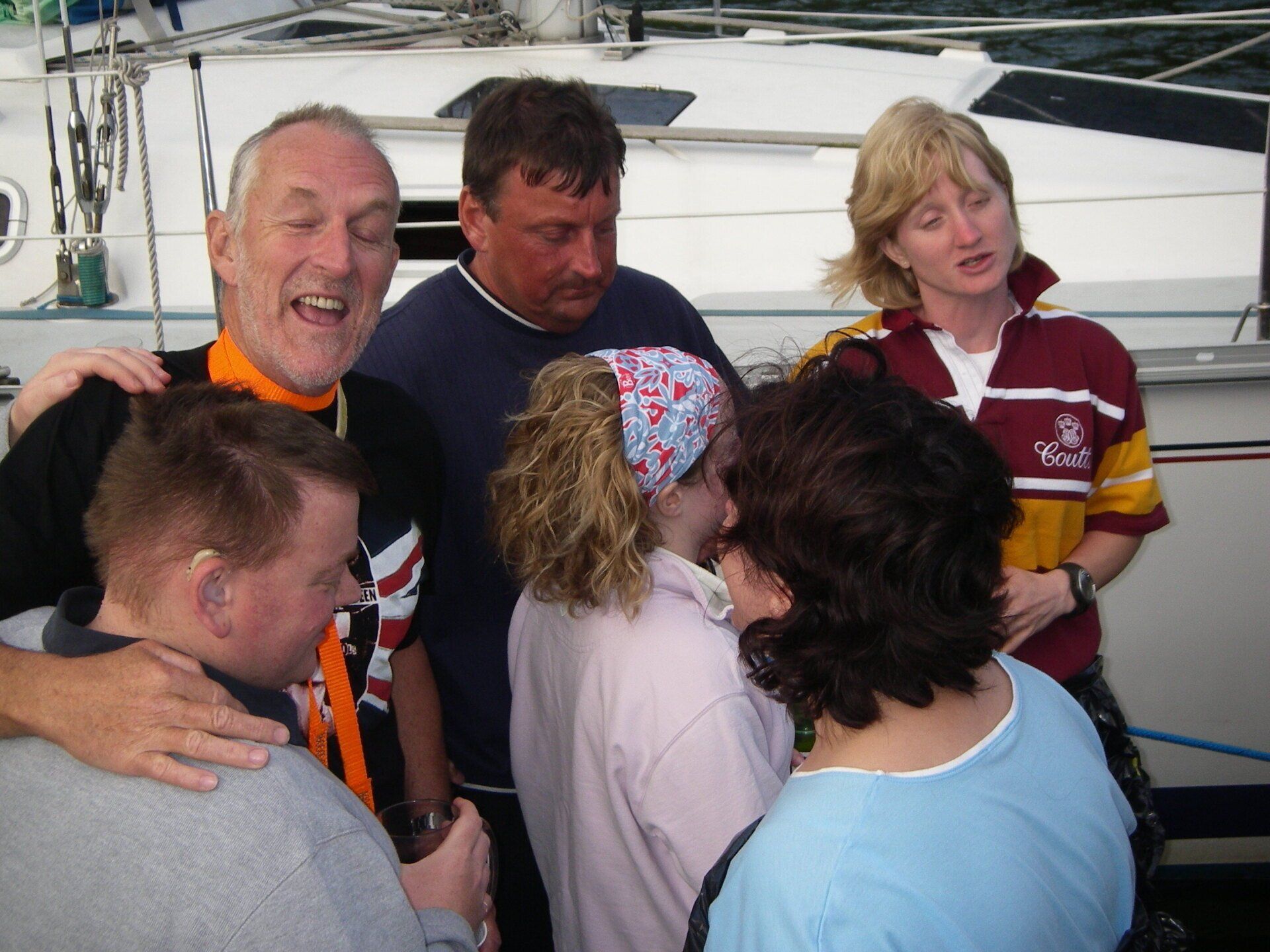 A group shot of six sighted and V.I. crew at the end of the day enjoying a drink together on the pontoon.