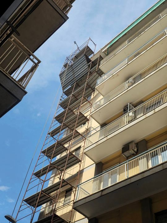 Impalcature su un grattacielo, cielo azzurro sullo sfondo.