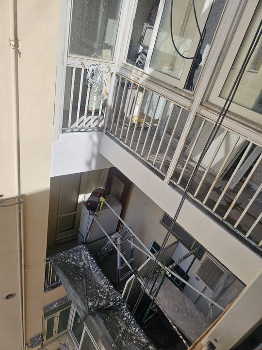 Vista su un cortile aperto con balconi e impalcature sottostanti.