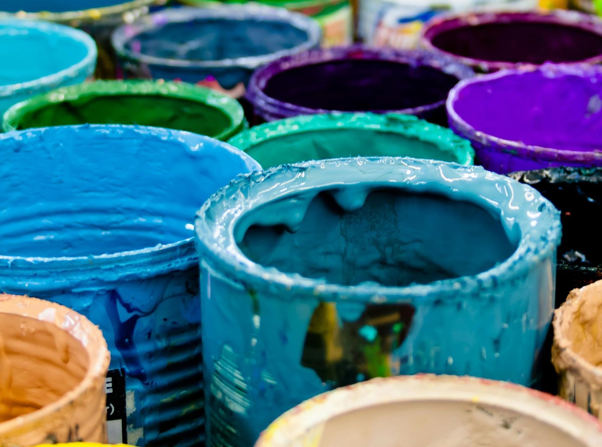 A bunch of buckets filled with different colors of paint