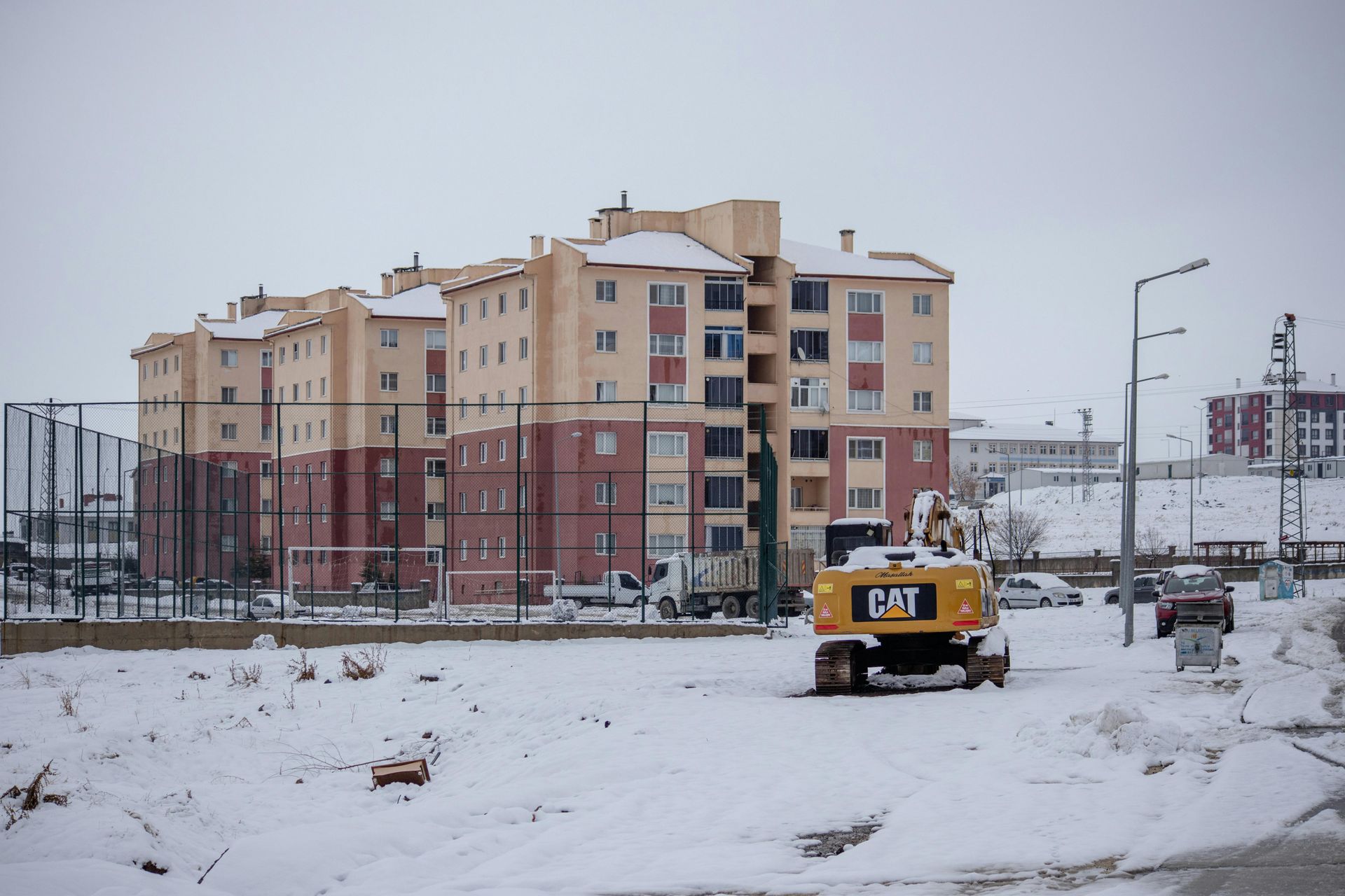 Apartment building and CAT excavator in a snowy landscape.