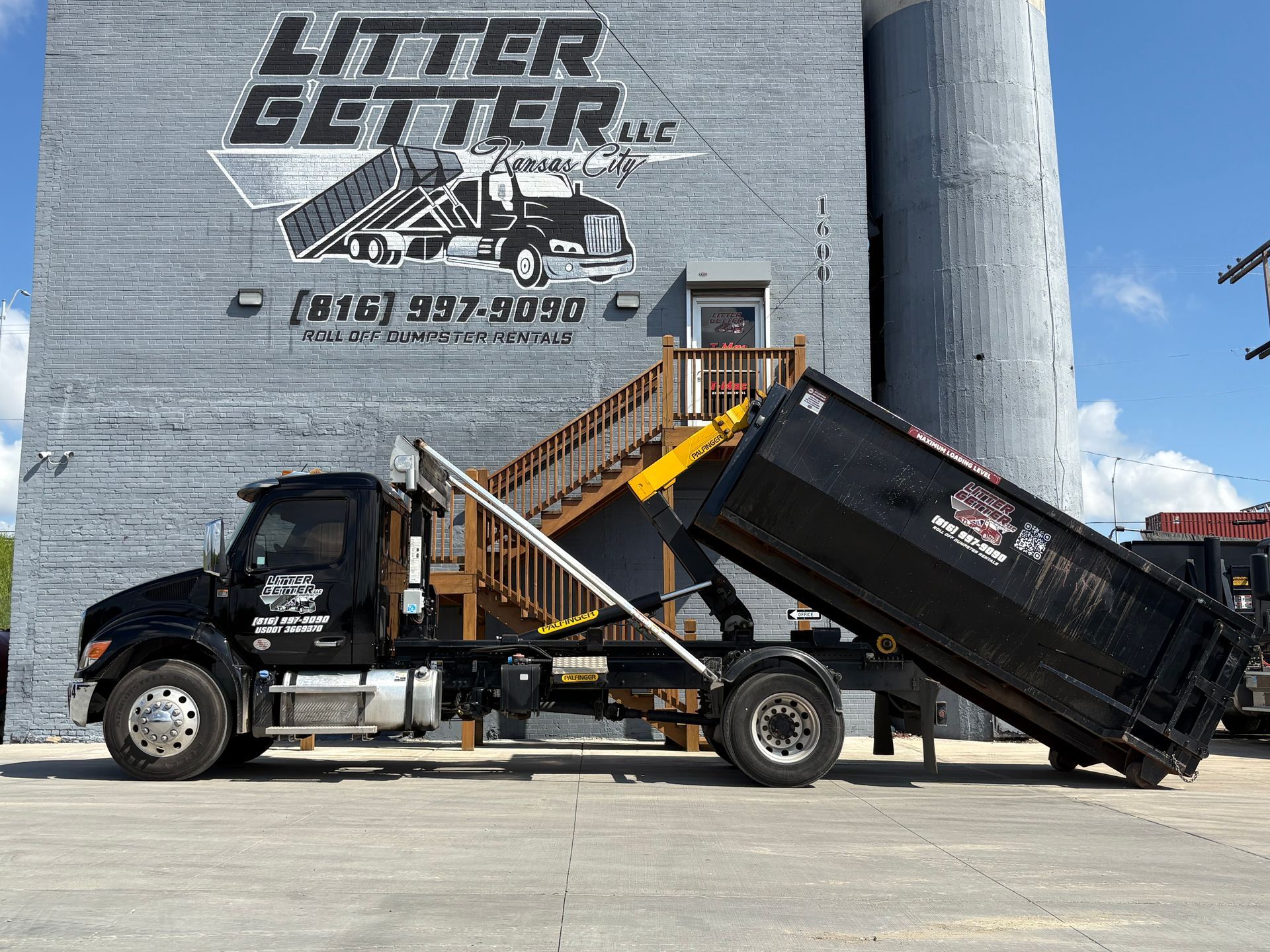 Black Litter Getter truck with 20 yard dumpster rental near a grey building in Kansas City, MO