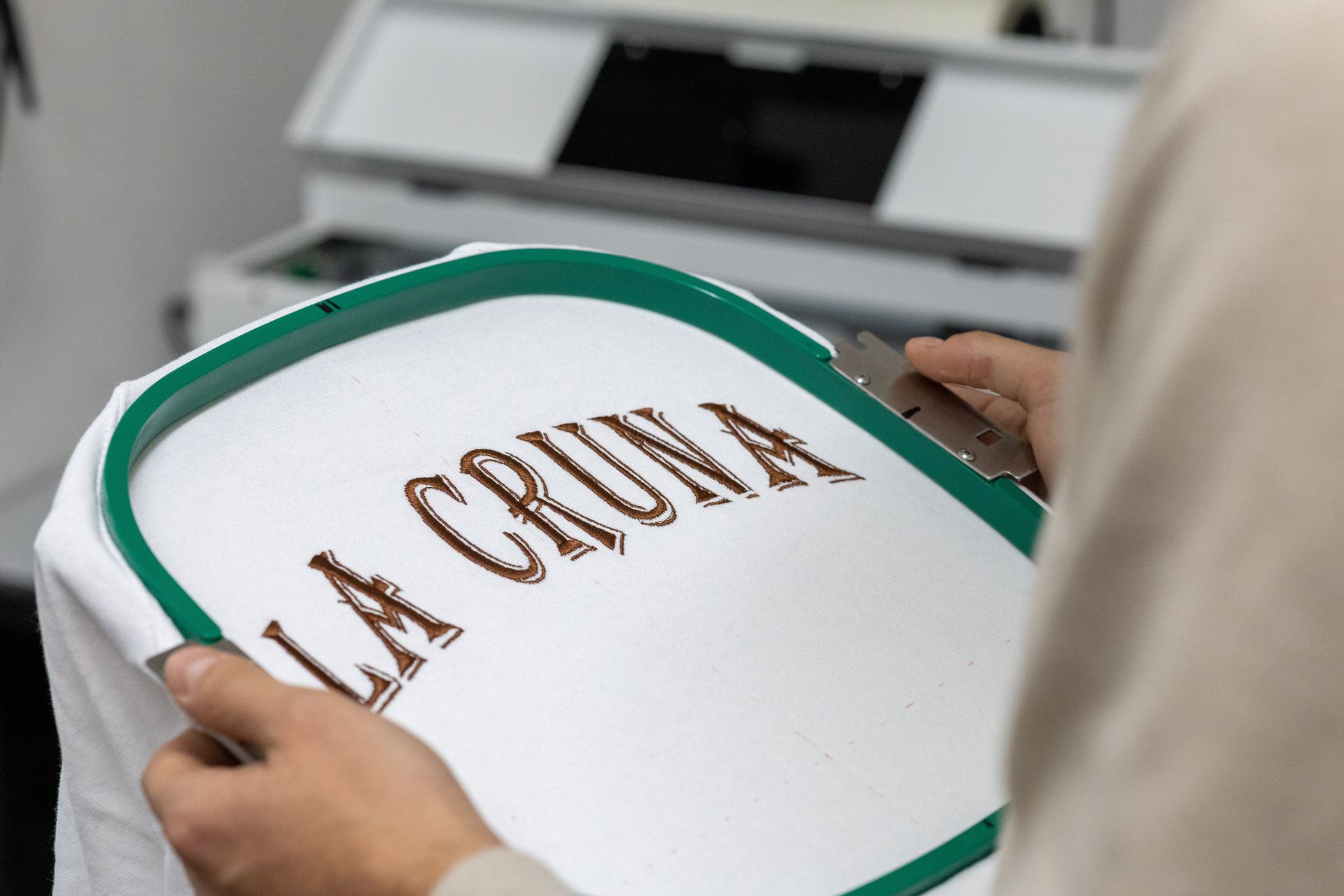 Persona che tiene in mano un cerchio di stoffa con la scritta ricamata 