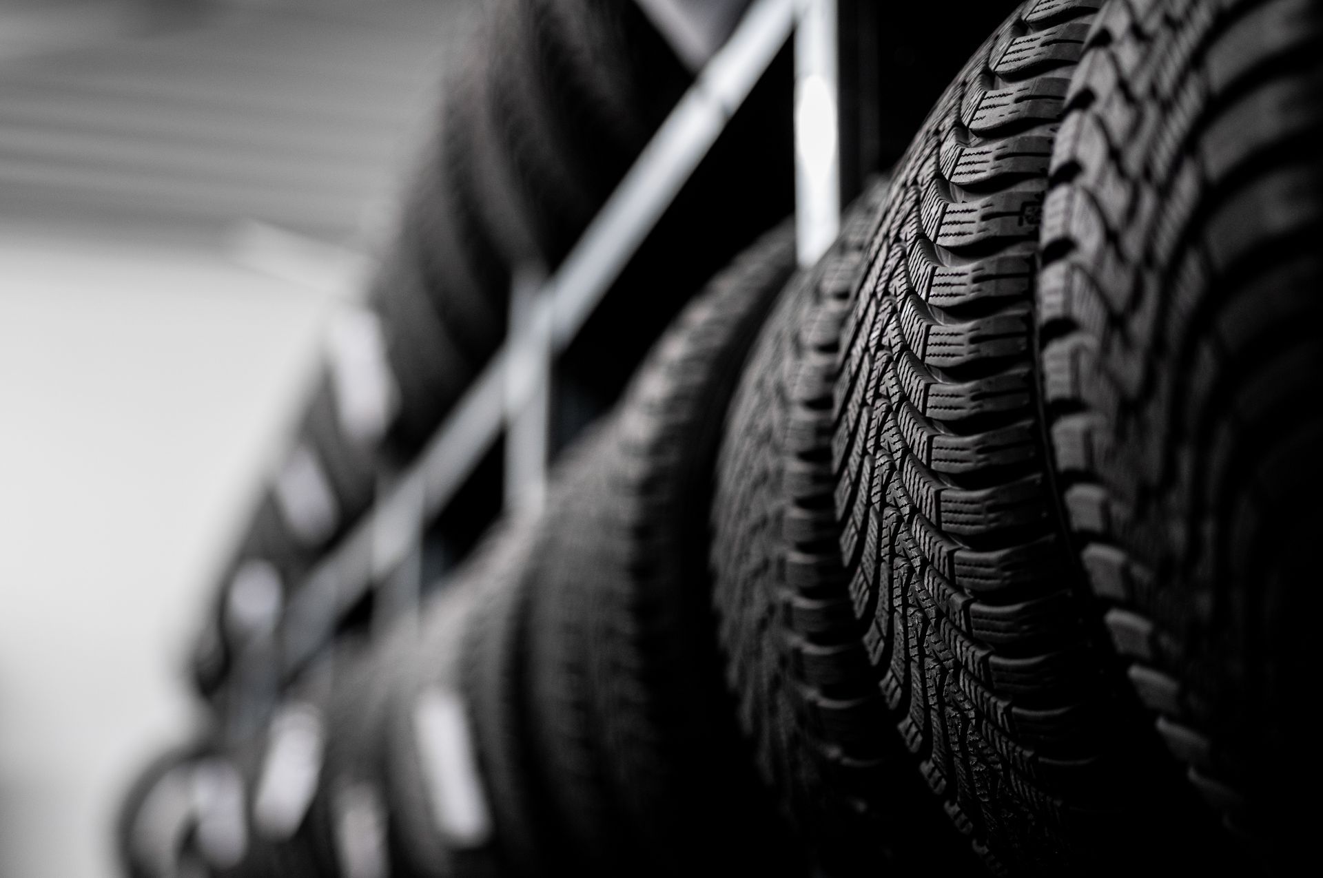 Rows of black tires on a rack in a garage, shown in shallow focus