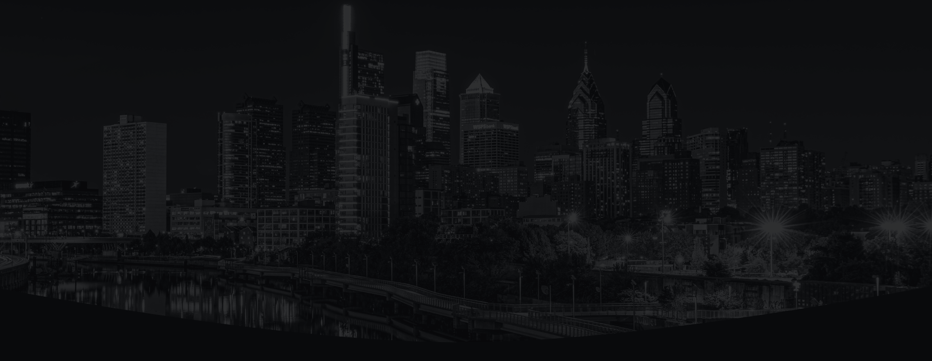 Dark city skyline at night with illuminated buildings and reflections on the water