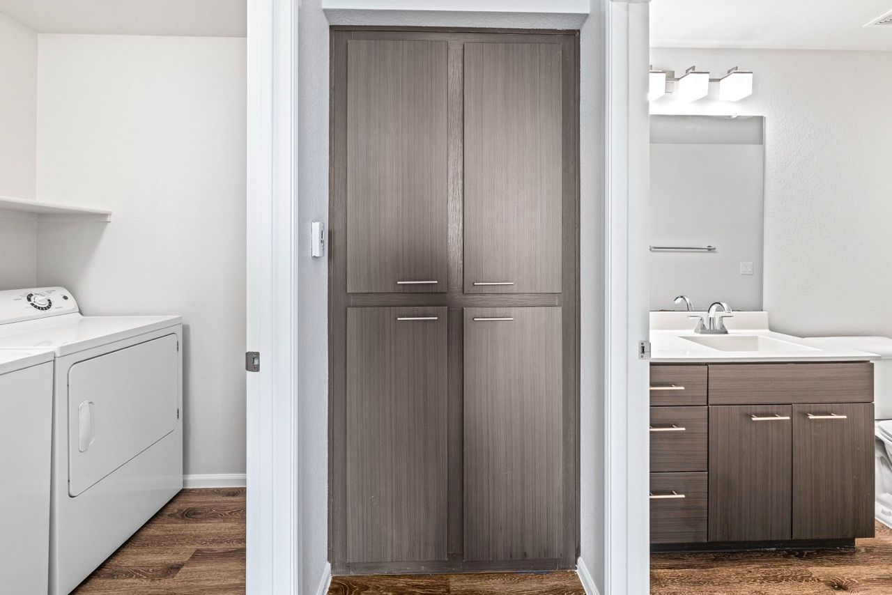 Laundry area with washer and dryer on the left, central storage cabinet, and bathroom vanity on the right.