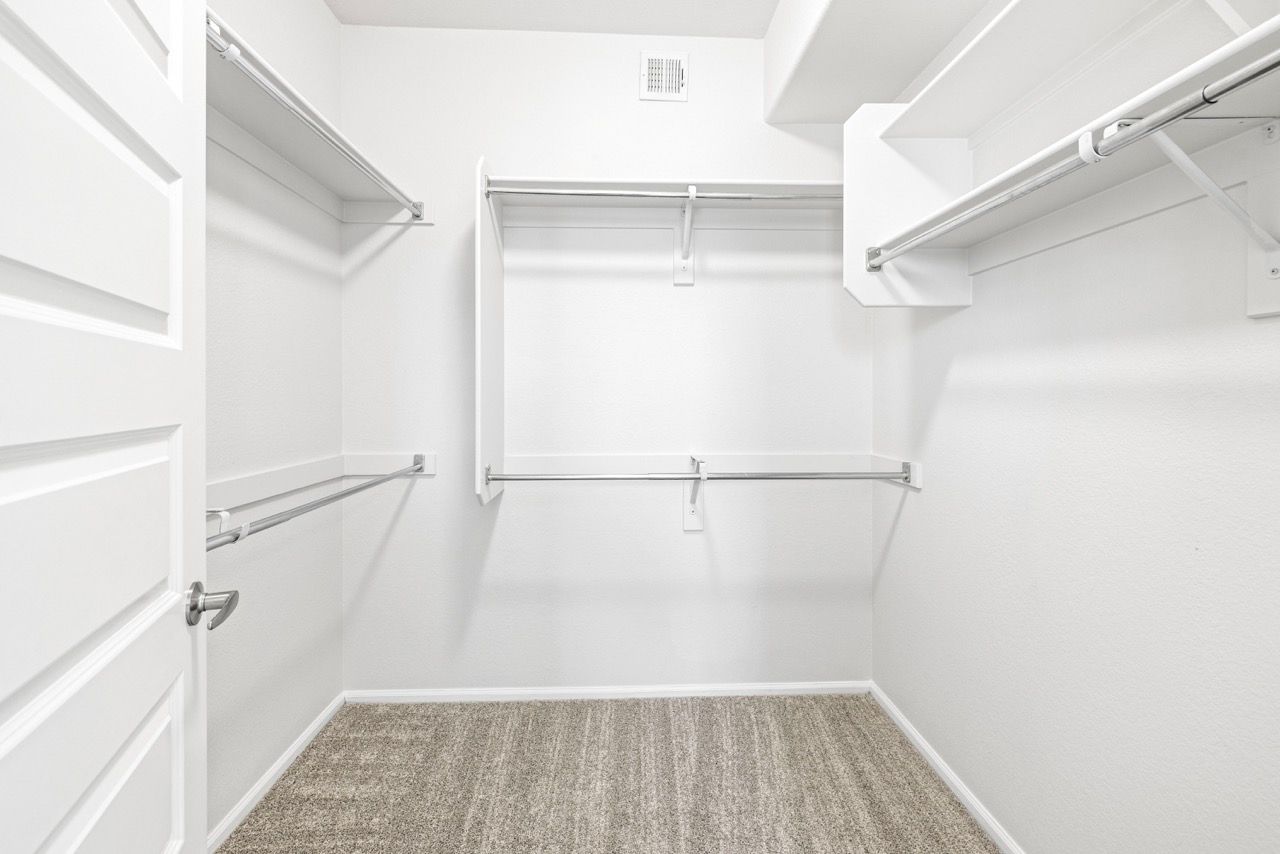 White walk-in closet with hanging rods and built-in shelves.