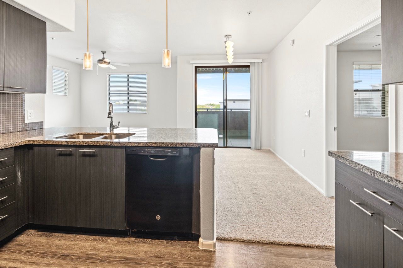 Open-concept kitchen with granite countertops, dark wood cabinets, and a dishwasher.
