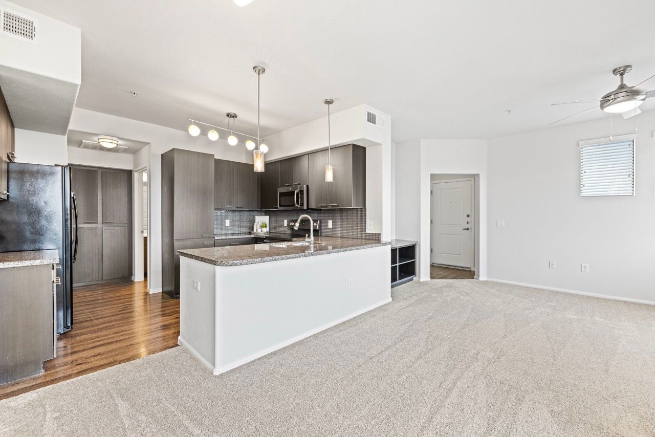 Open-concept kitchen with island, dark cabinets, and stainless appliances.