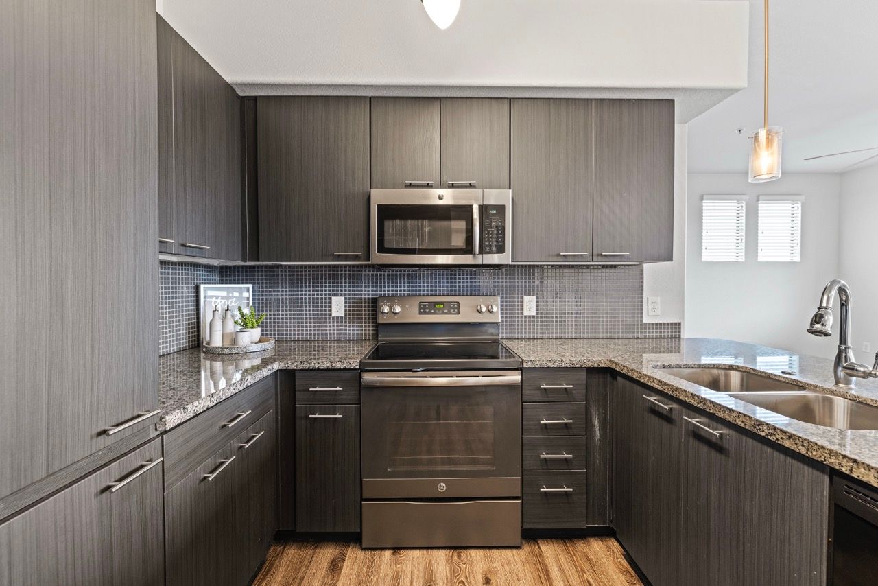 Modern kitchen with dark wood cabinets, stainless steel appliances, and granite countertops.
