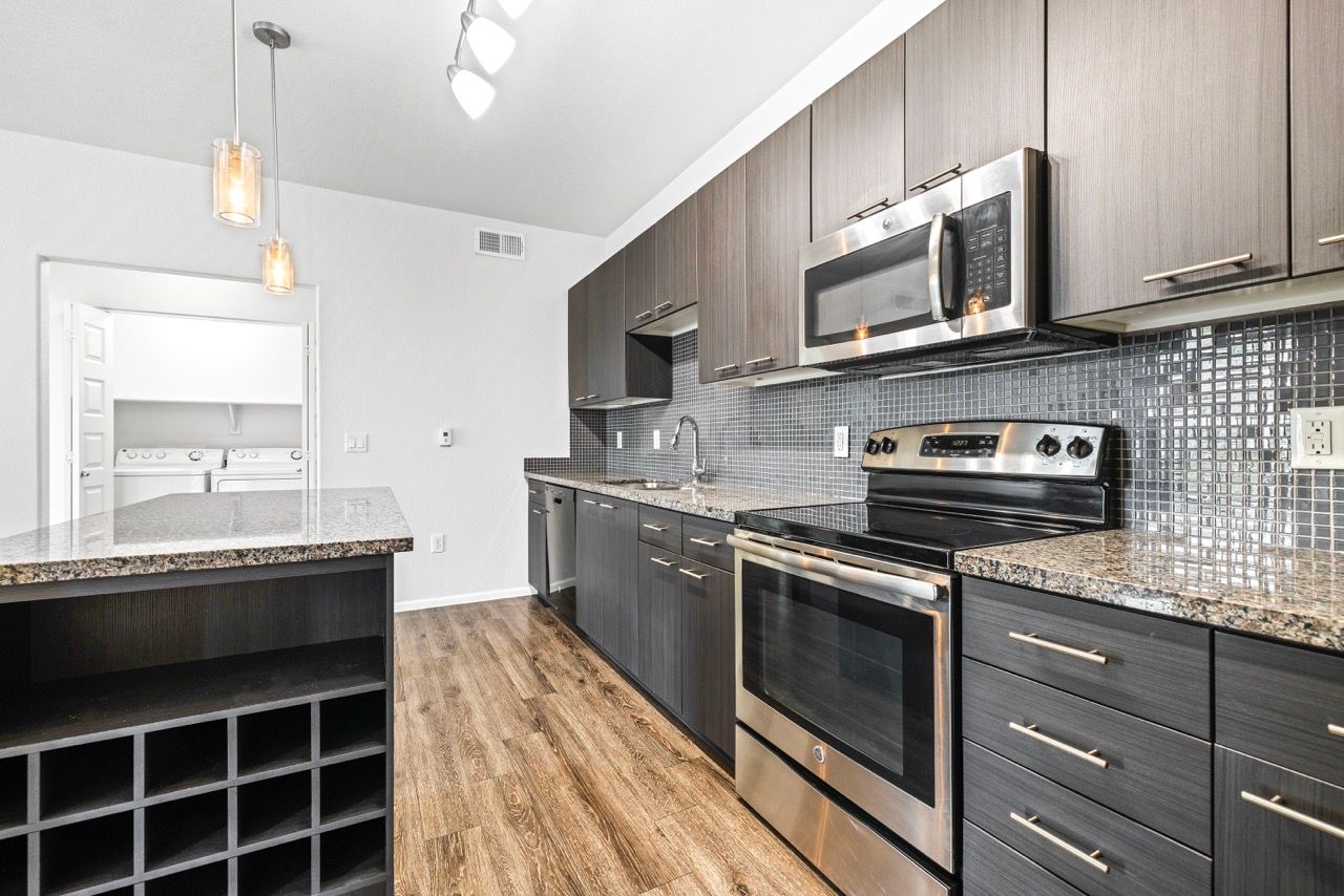 Modern kitchen with stainless steel appliances, granite countertops, and dark wood cabinets.
