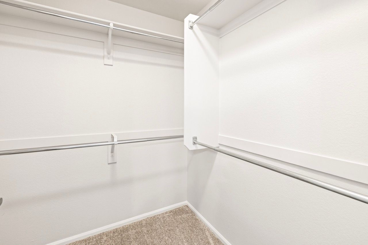 White walk-in closet with dual garment rods on opposite walls.